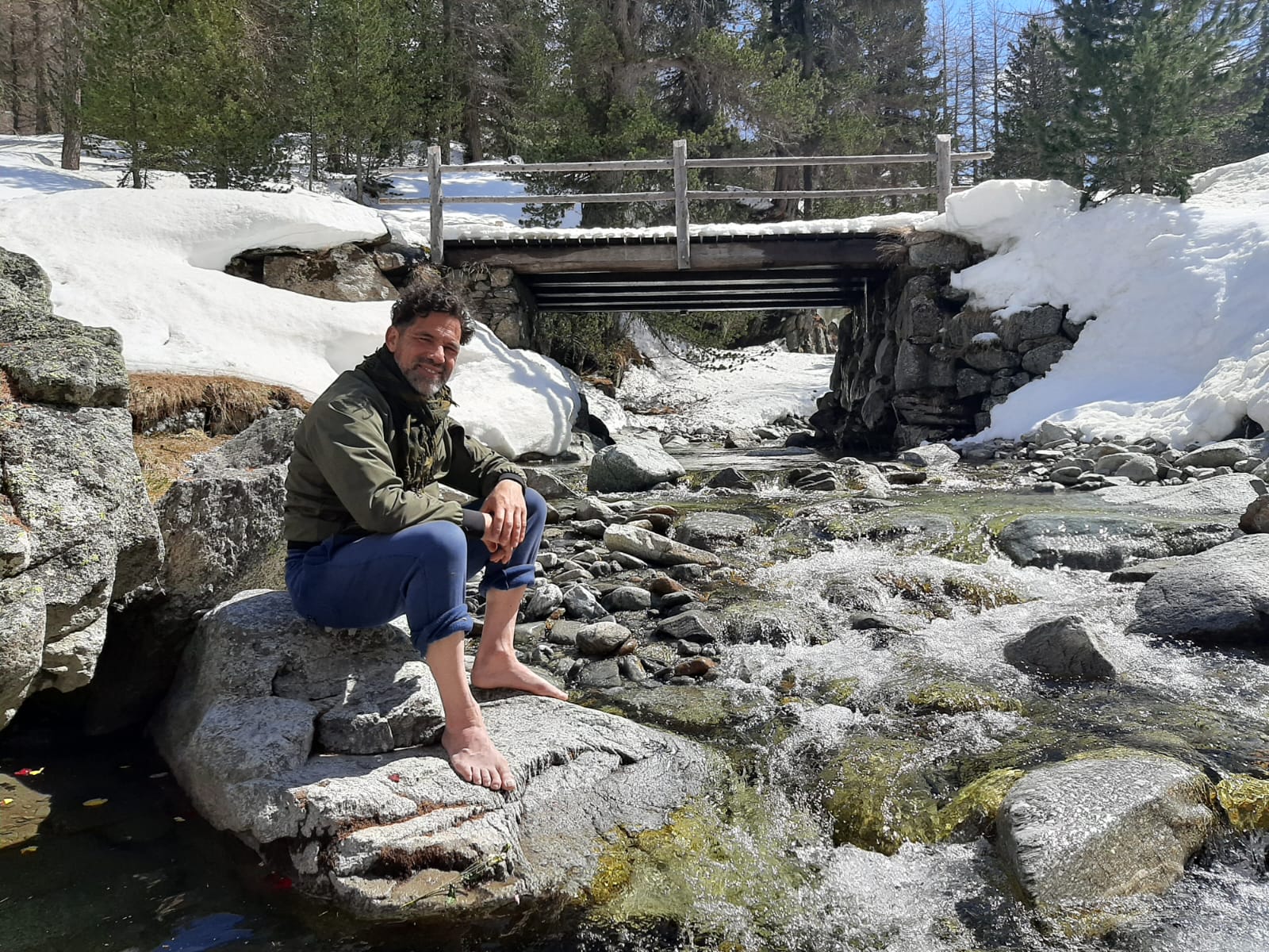Mike seduto accanto a un torrente di montagna innevato a Livigno