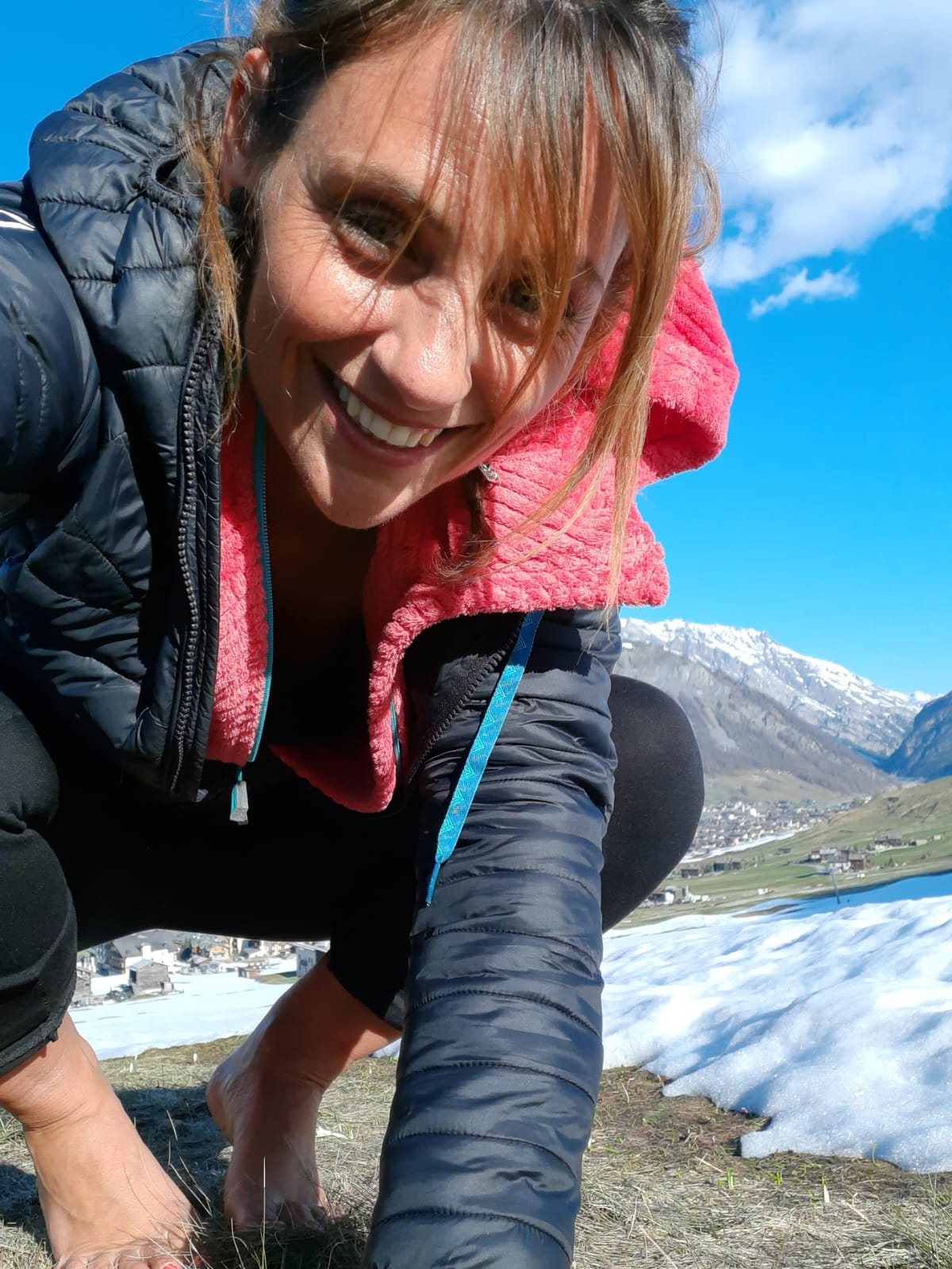Pamela sorride in primo piano su un prato d’alta quota, con la valle di Livigno sullo sfondo